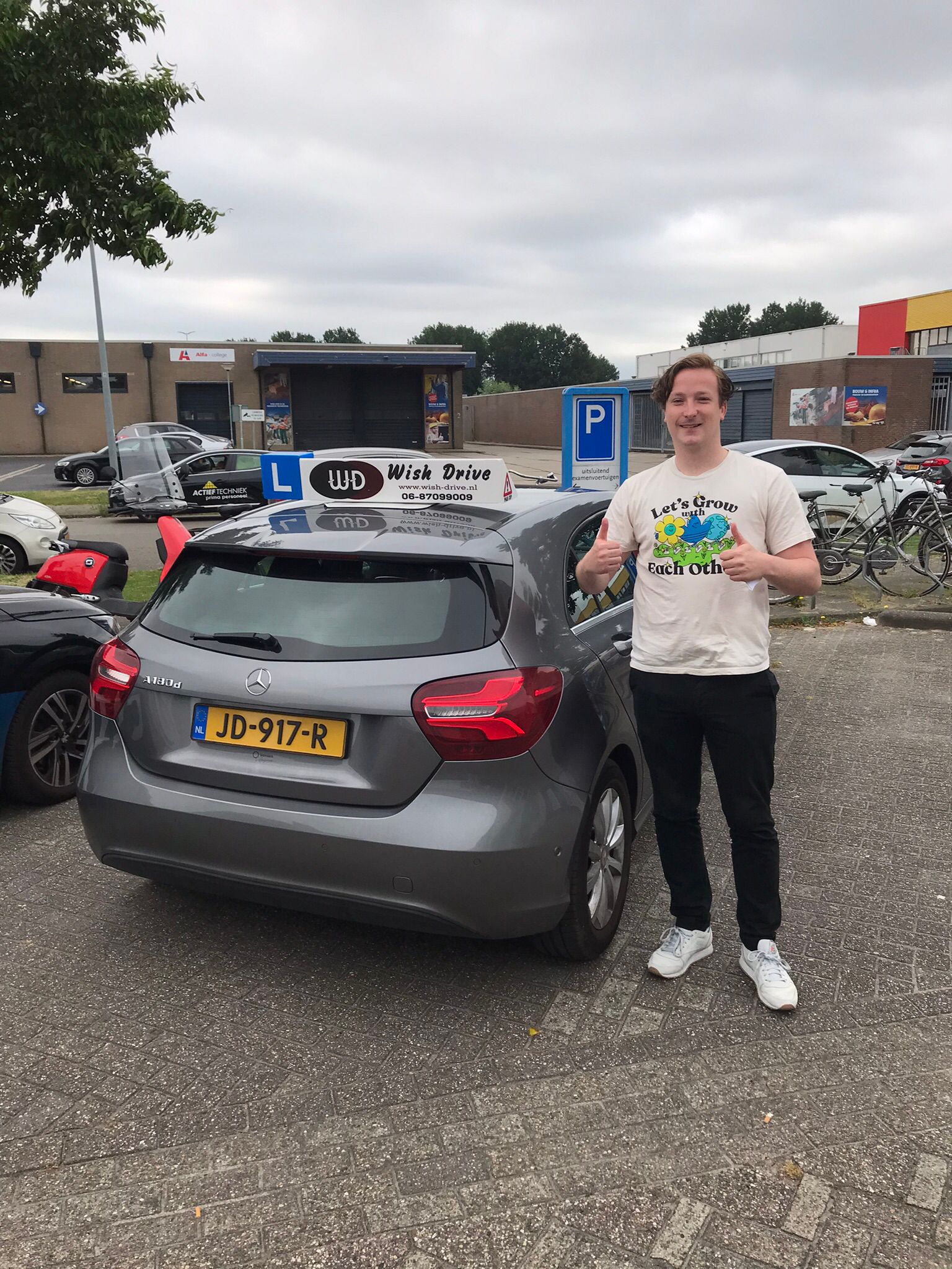 Geslaagde leerling naast de lesauto van Wish Drive